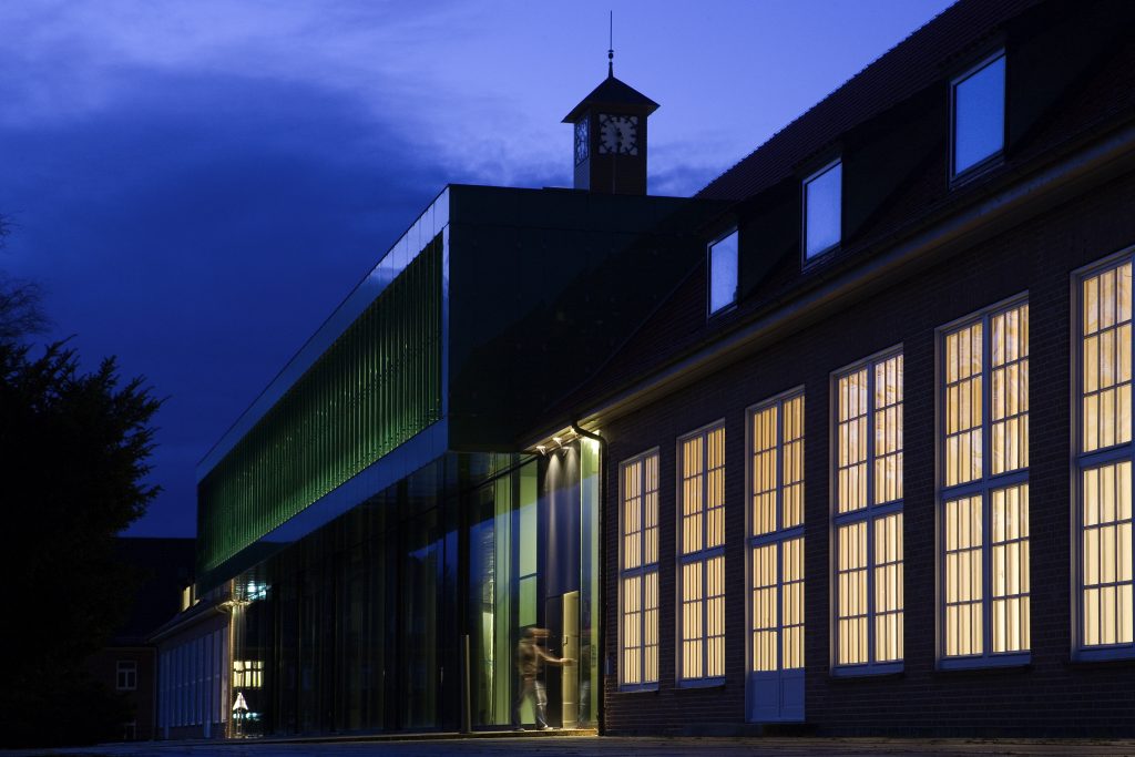 Evening view of the IRC, with rows of warmly lit windows, with the sky beginning to darken. 