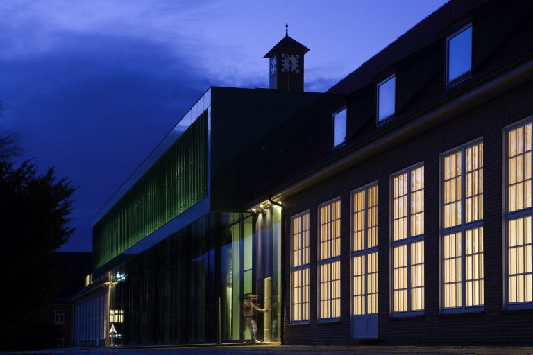 Evening view of the IRC, with rows of warmly lit windows, with the sky beginning to darken. 